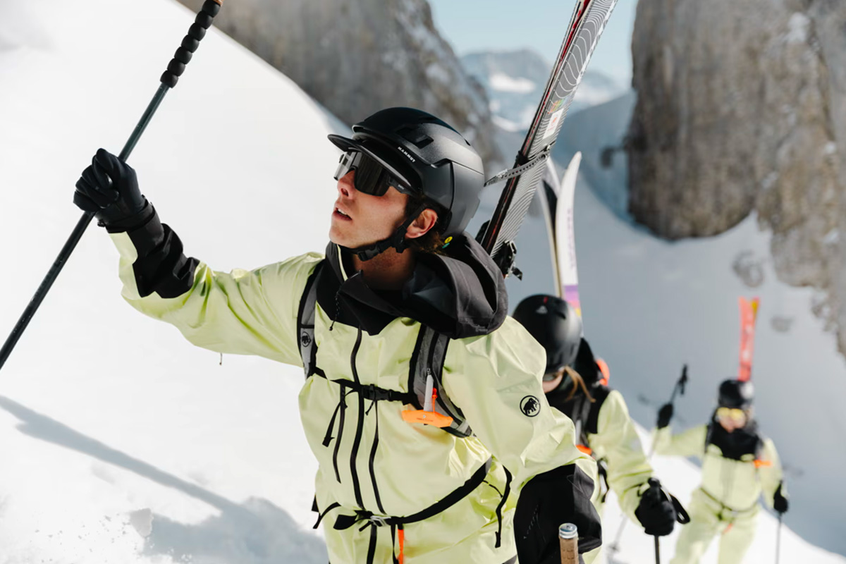 Skier ascending through pristine backcountry terrain in Austria wearing Mammut freeride gear and carrying essential safety equipment.